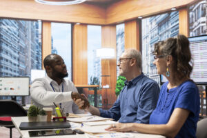 A young business professional shaking hands with one of his clients.