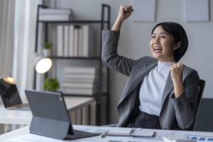 A business professional happily raising her fist in celebration of a win at work.
