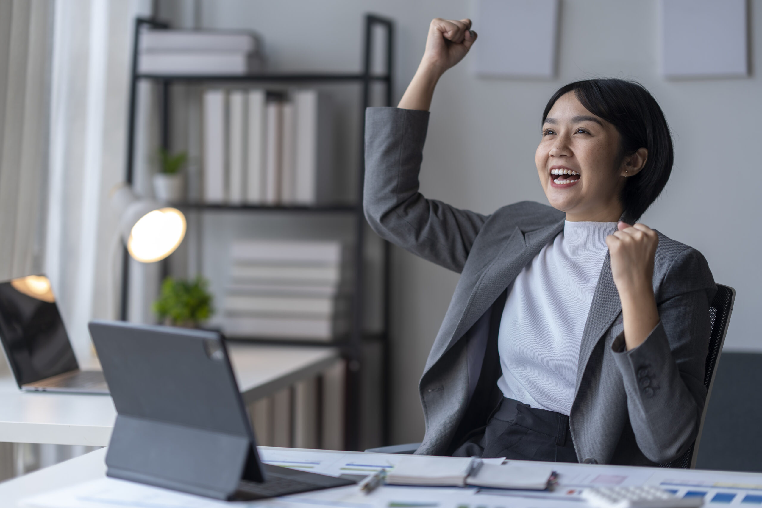 A business professional happily raising her fist in celebration of a win at work.