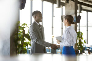 Two business professionals shaking hands in a cozy office environment