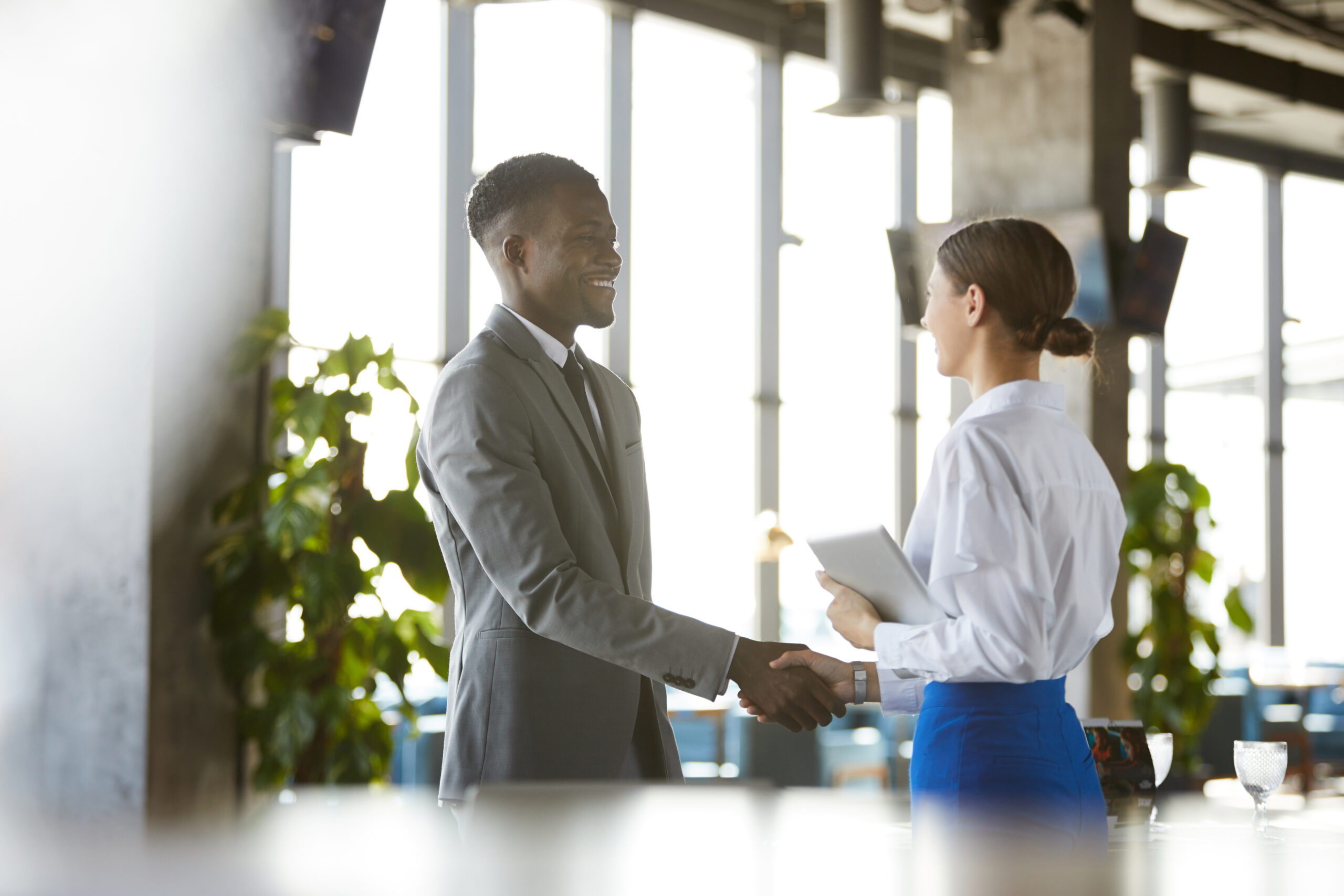 Two business professionals shaking hands in a cozy office environment