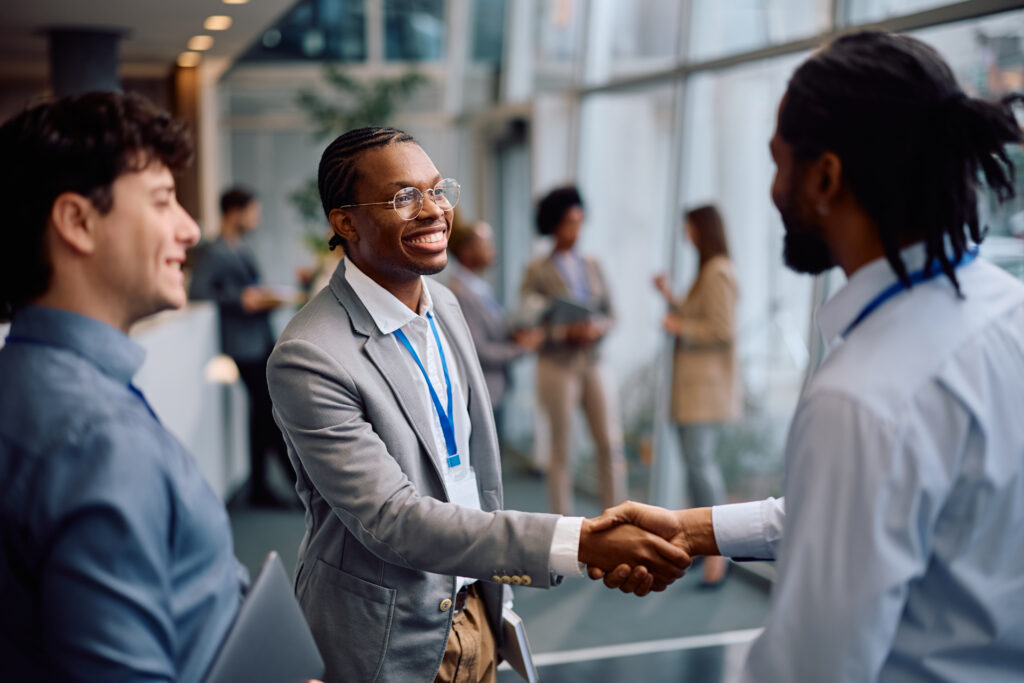 Two young professionals shaking hands in a corporate event setting